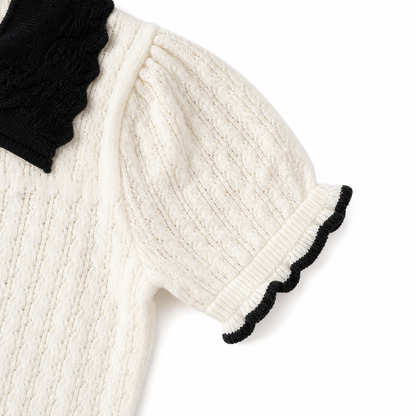 Close-up of the textured short sleeve and black edge trim on an ivory girls knit top.