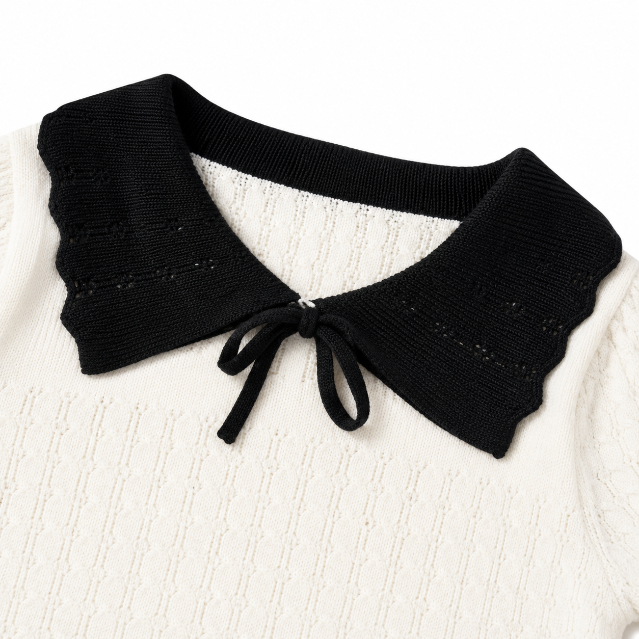 Close-up of the black bow and contrast collar on an ivory toddler girl knit top.