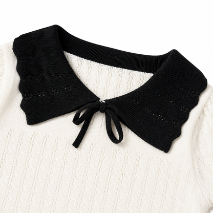 Close-up of the black bow and contrast collar on an ivory toddler girl knit top.