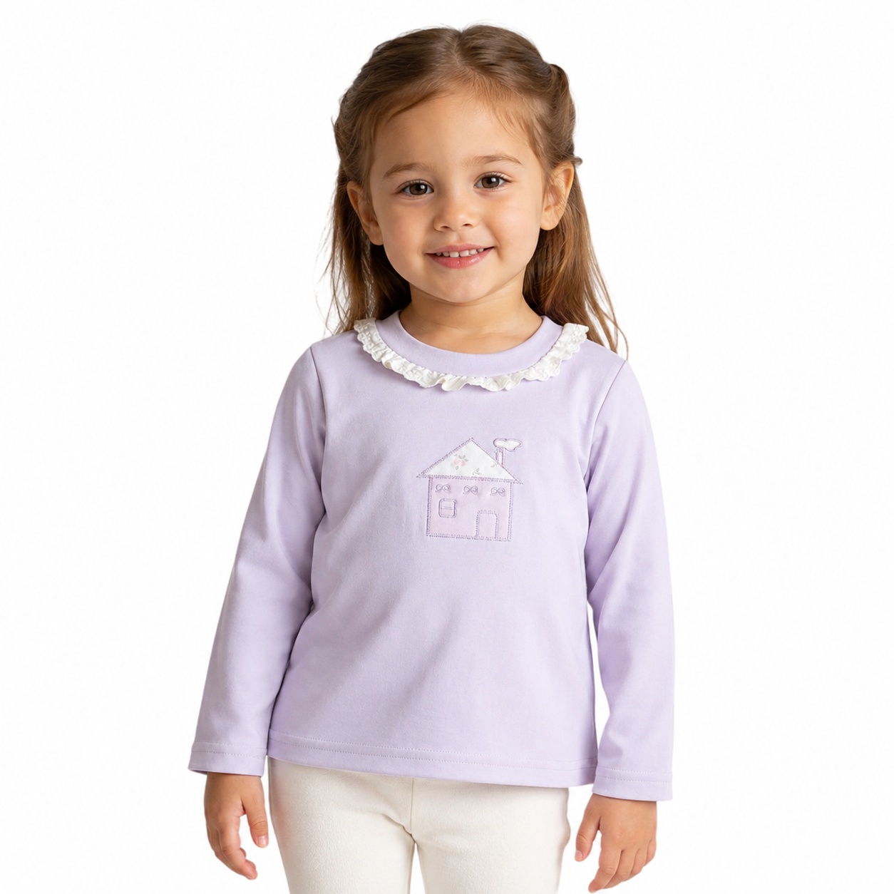Girl model wearing the Lavender cotton long sleeve ruffle collar top with storybook house embroidery on a white studio background.