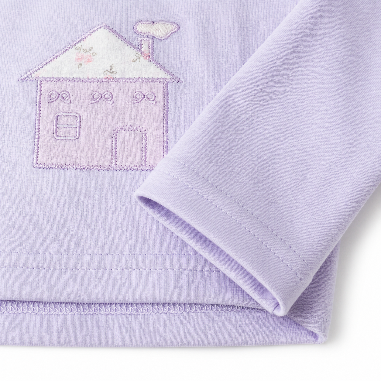 Close-up of the storybook house embroidery on the Lavender girls cotton long sleeve top.