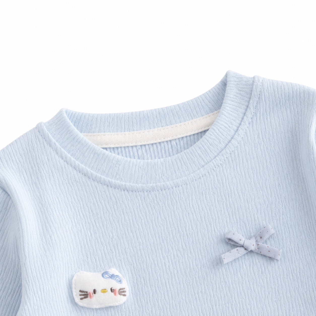 Close-up of the round neckline detail on a light blue girls cotton top.