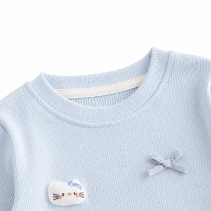 Close-up of the round neckline detail on a light blue girls cotton top.