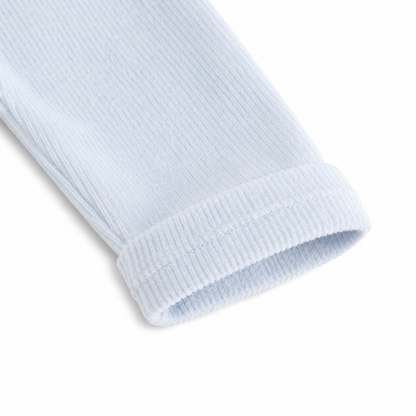 Close-up of the sleeve cuff detail on a light blue girls long sleeve cotton top.