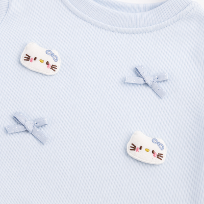 Close-up of the bow applique and patch detail on a light blue girls ruffle top.