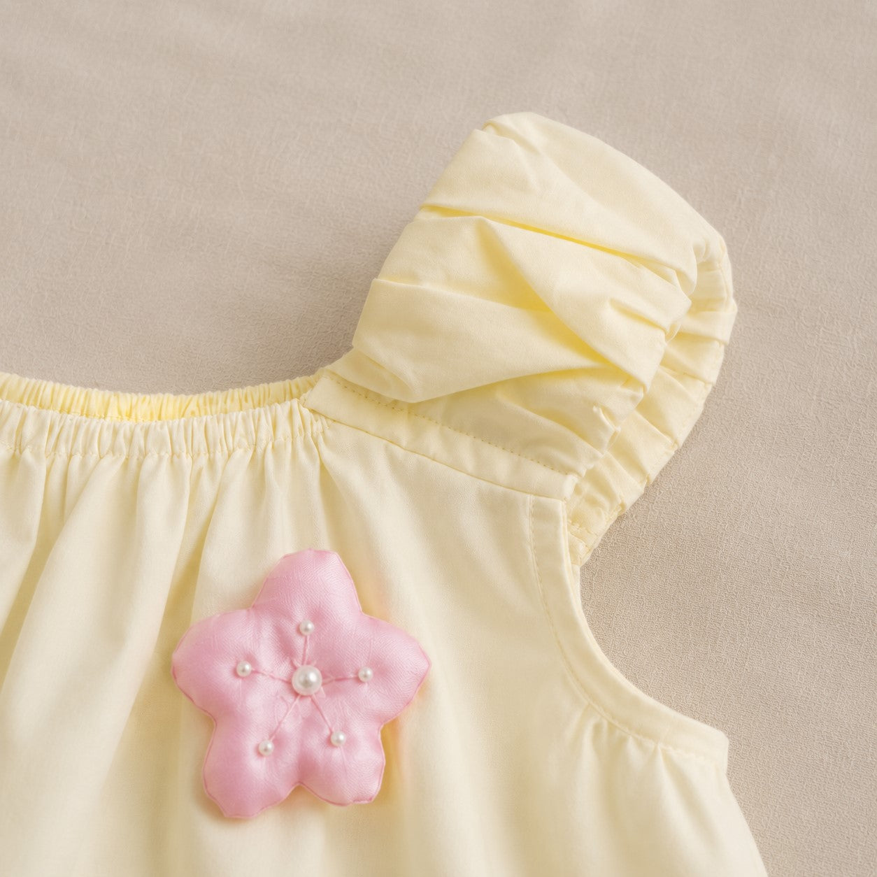 Close-up of the Lila Bloom Set pink flower applique and gathered shoulder detail.