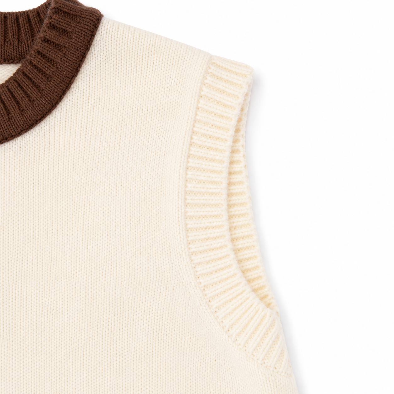 Close-up of the ribbed armhole and knit construction on the ivory brown kids cardigan vest.