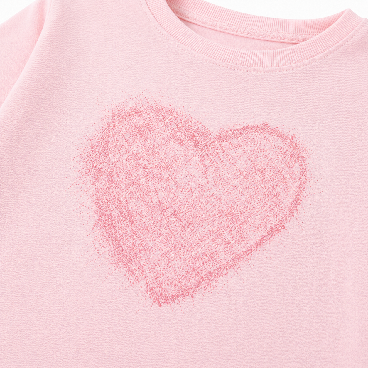 Close-up of the soft pink heart graphic on the girls long sleeve tee.