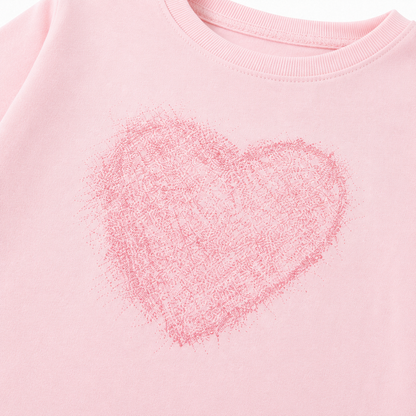 Close-up of the soft pink heart graphic on the girls long sleeve tee.