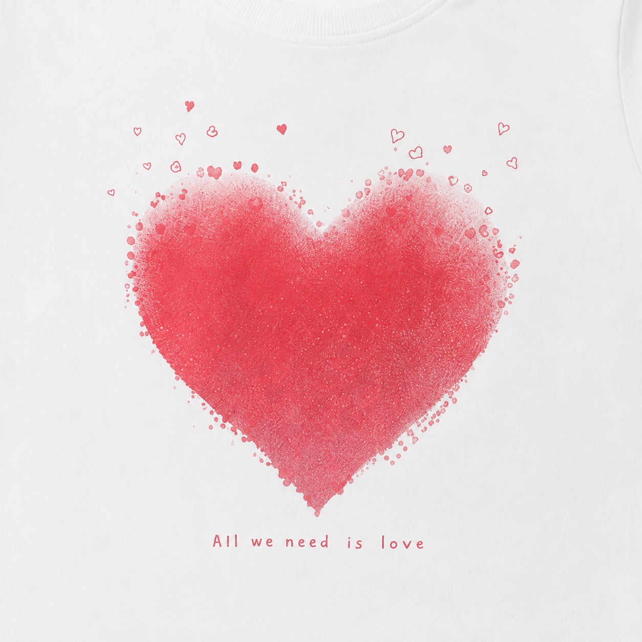 Close-up of the red heart graphic and All we need is love text on the white girls tee.