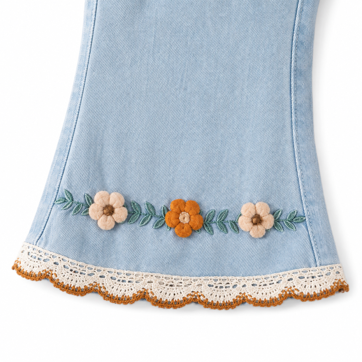 Close-up of the floral embroidery near the hem of the light blue girls jeans.