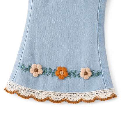 Close-up of the floral embroidery near the hem of the light blue girls jeans.