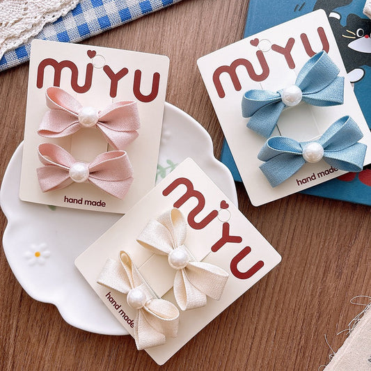 Meadow Pearl Bow Clip Set in assorted pink, blue, and ivory bow hair clips.