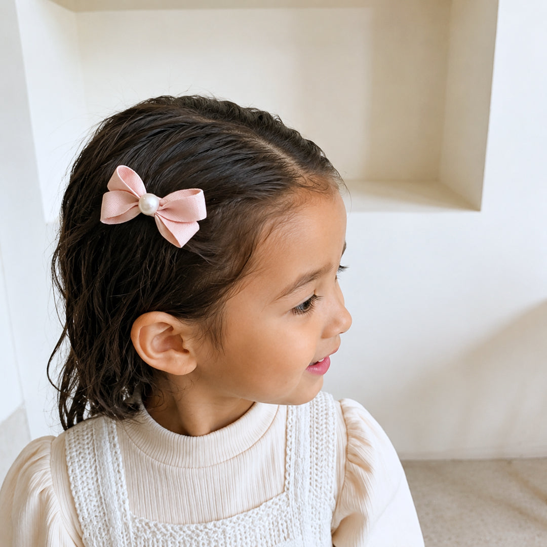 Girl wearing the Meadow Pearl Bow Clip Set with a soft pink bow hair clip.