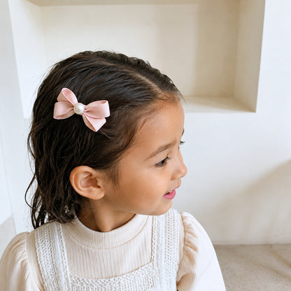 Girl wearing the Meadow Pearl Bow Clip Set with a soft pink bow hair clip.