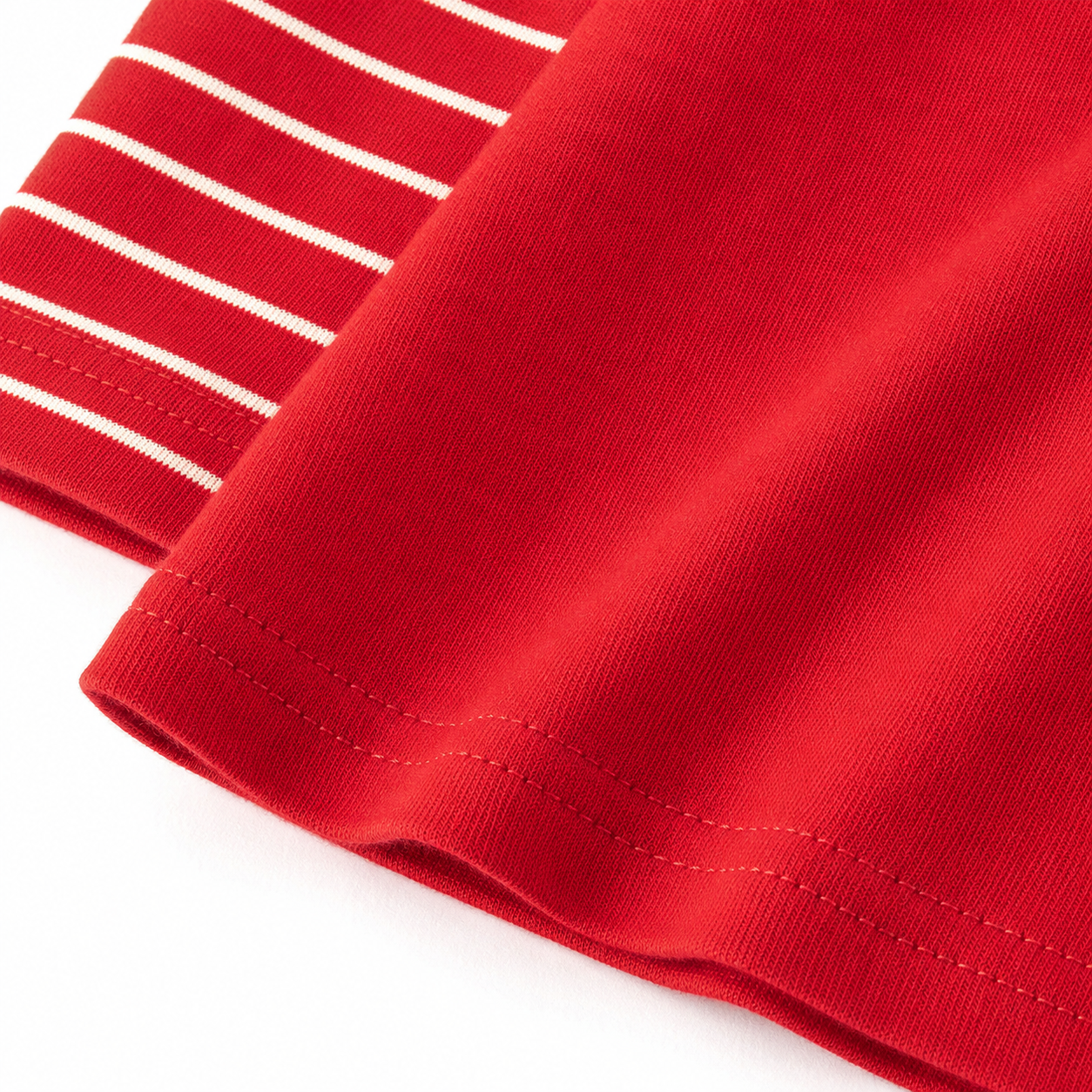 Close-up of the red cotton fabric and hem detail on the girls holiday dress.