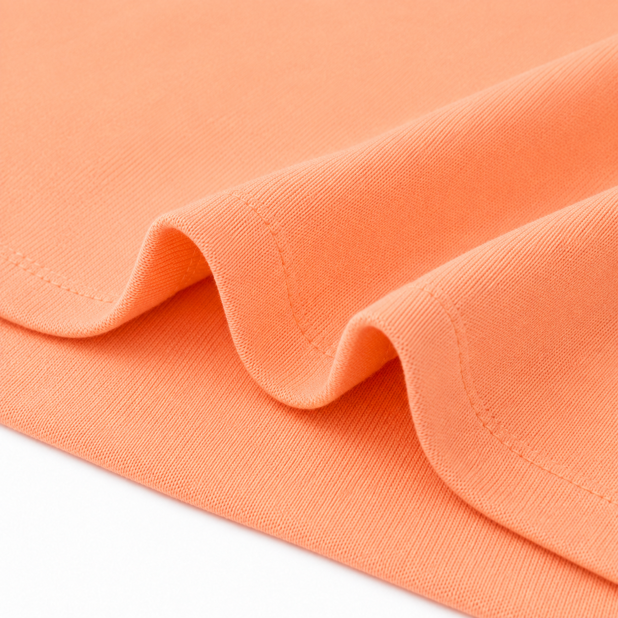 Close-up of the hem stitching and cotton fabric on the peach long sleeve kids shirt.
