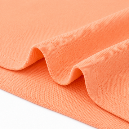 Close-up of the hem stitching and cotton fabric on the peach long sleeve kids shirt.