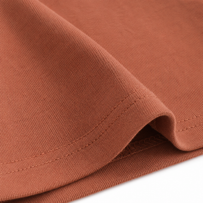 Close-up of the hem stitching and cotton fabric on the terracotta long sleeve kids shirt.