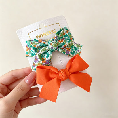 Petal Bloom Bow Clip Set with green floral bow and orange bow hair clips.