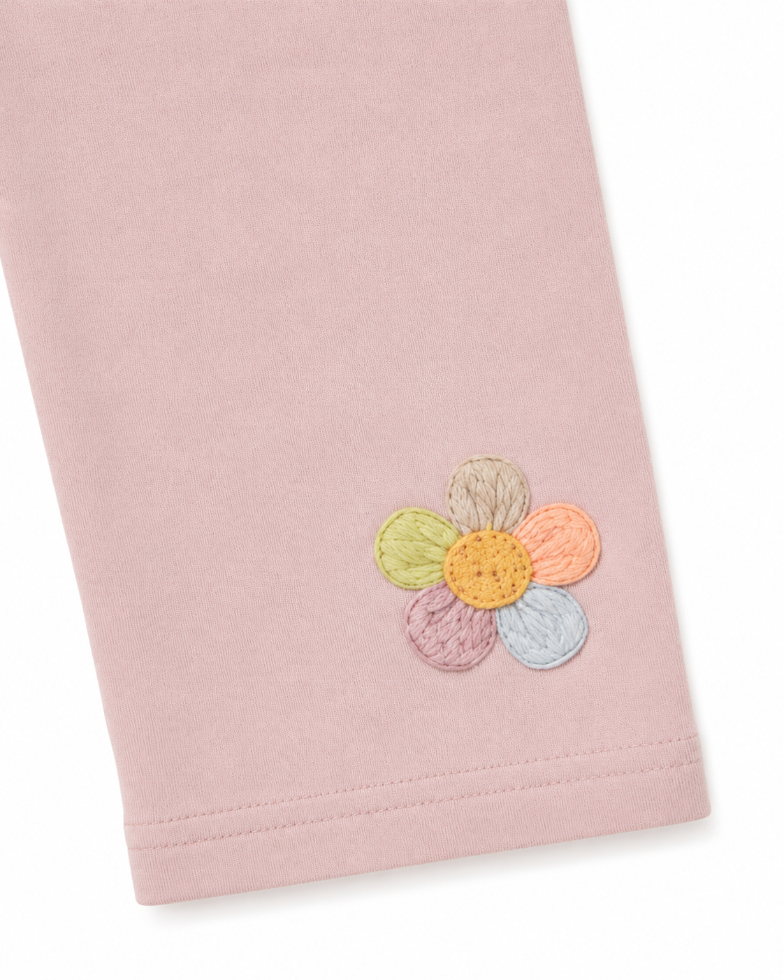 Close-up of the colorful flower applique near the hem of the blush pink leggings.