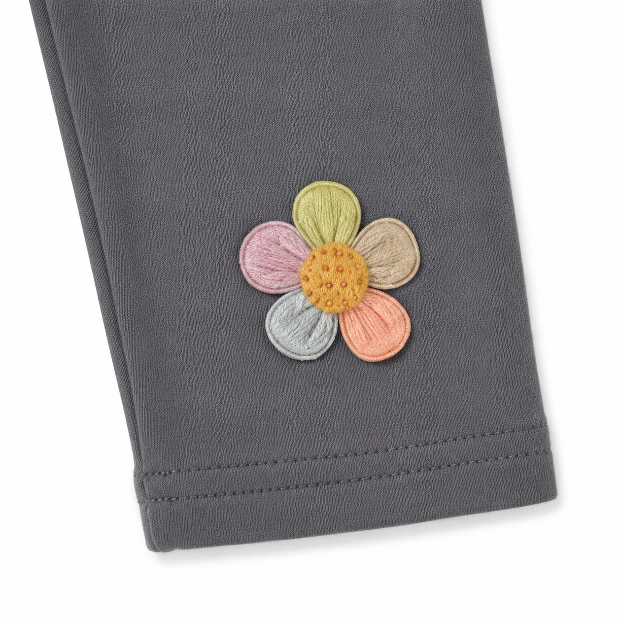 Close-up of the colorful flower applique near the hem of the charcoal gray leggings.