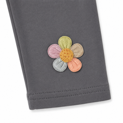 Close-up of the colorful flower applique near the hem of the charcoal gray leggings.