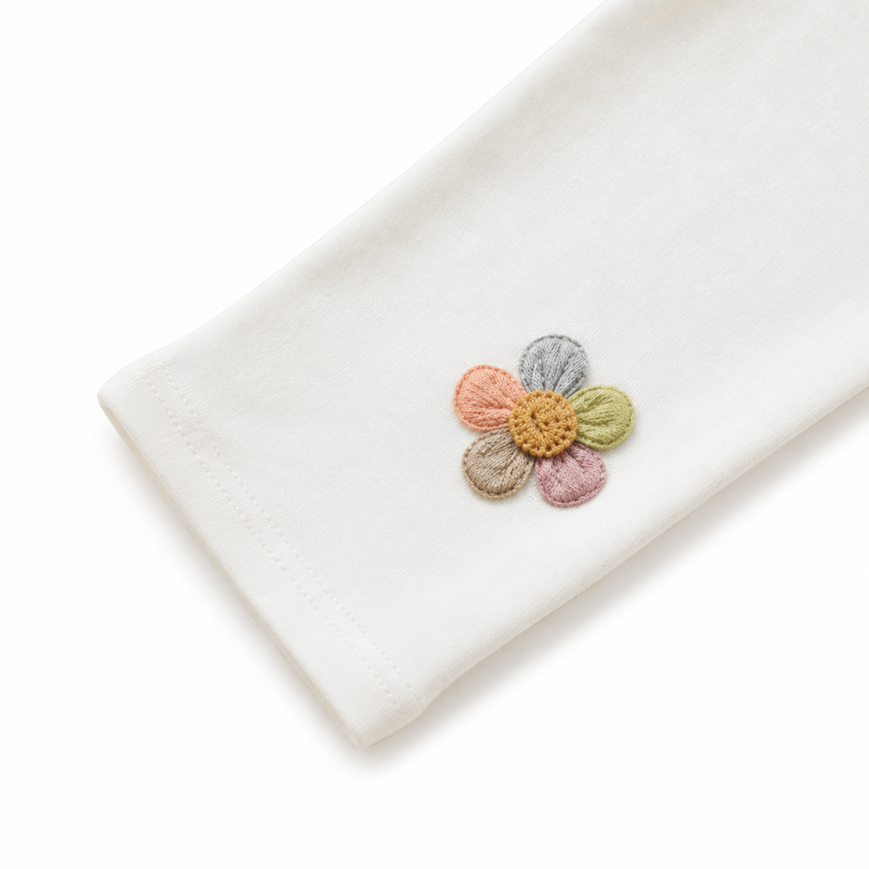 Close-up of the colorful flower applique near the hem of the ivory leggings.