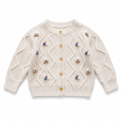 Front flat lay of the ivory girls cable knit cardigan with colorful pom blossom details.