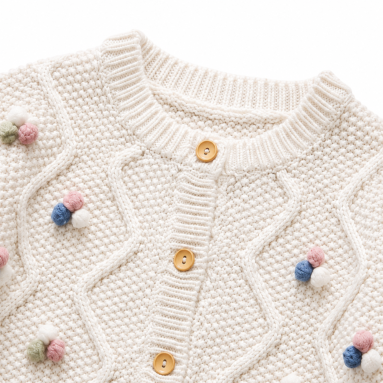 Close-up of the ivory cardigan neckline, buttons, cable knit pattern, and pom blossom details.