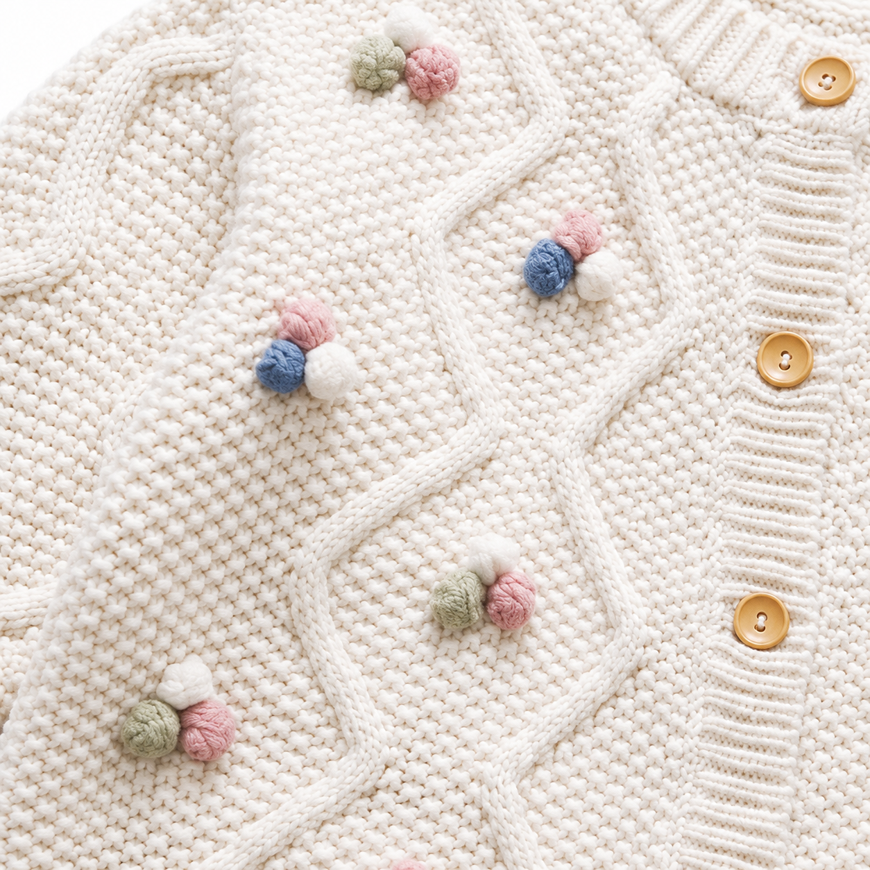 Close-up of the colorful pom blossom details and button-front cable knit design.