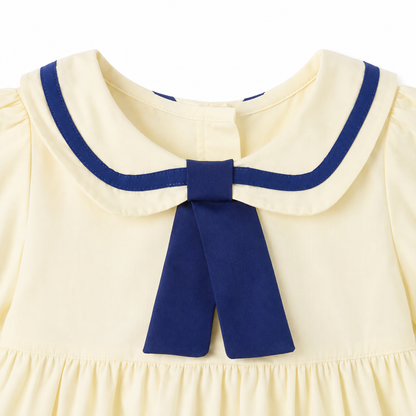 Close-up of the navy bow detail on the ivory girls sailor dress.