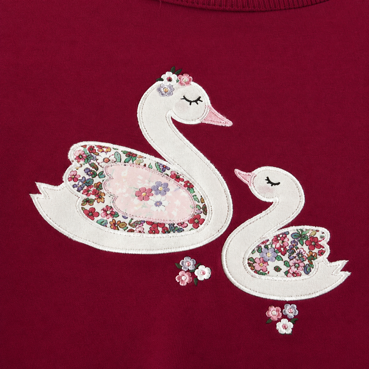 Close-up of the double swan applique and floral detail on the girls sweatshirt.