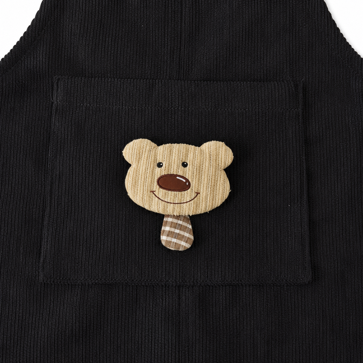 Close-up of the bear applique pocket on the black corduroy overalls.