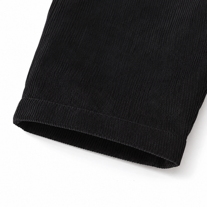 Close-up of the corduroy texture and pant leg hem on the black overalls.