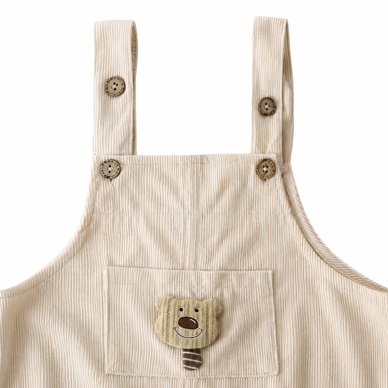 Close-up of the shoulder strap and button detail on the ivory overalls.