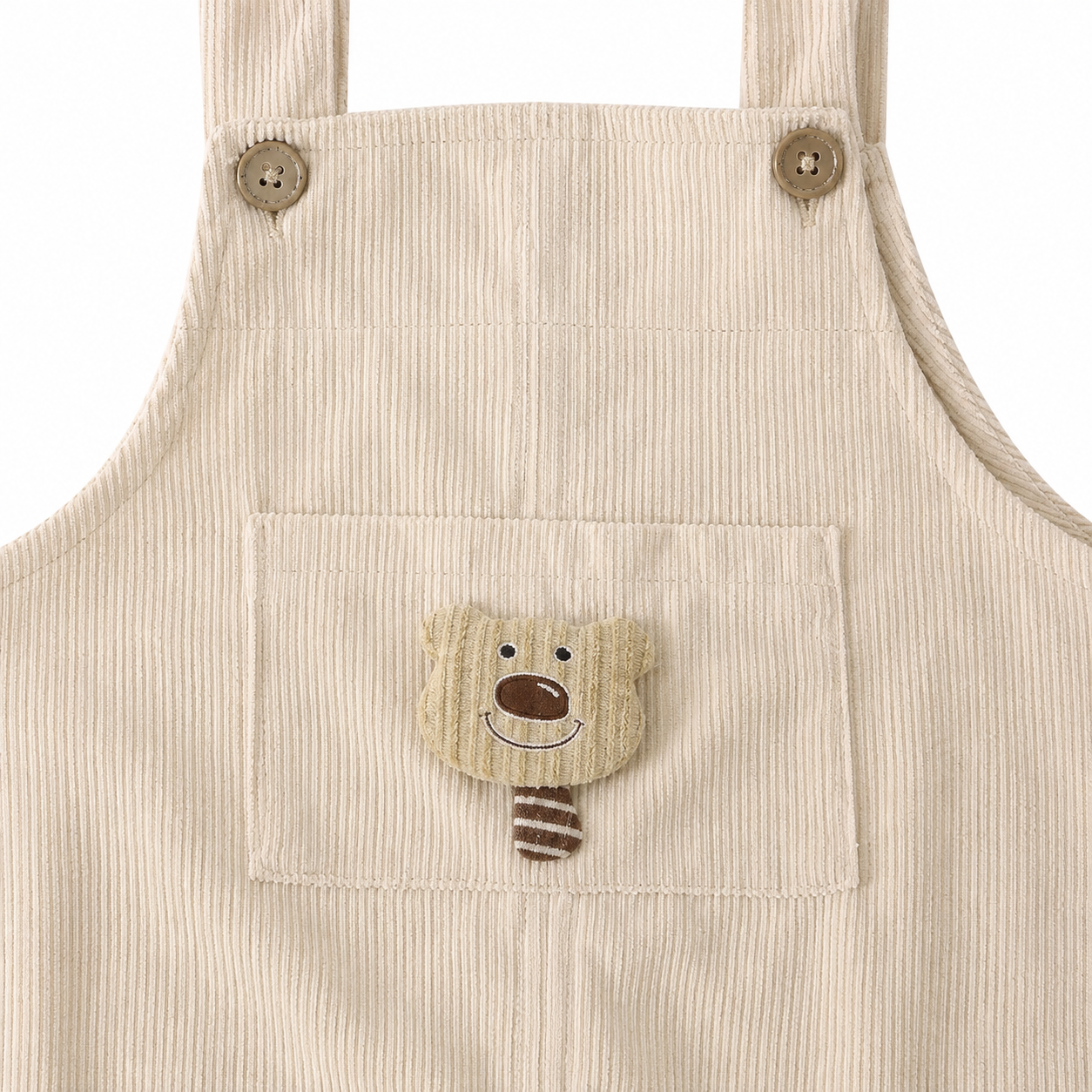 Close-up of the bear applique pocket on the ivory corduroy overalls.