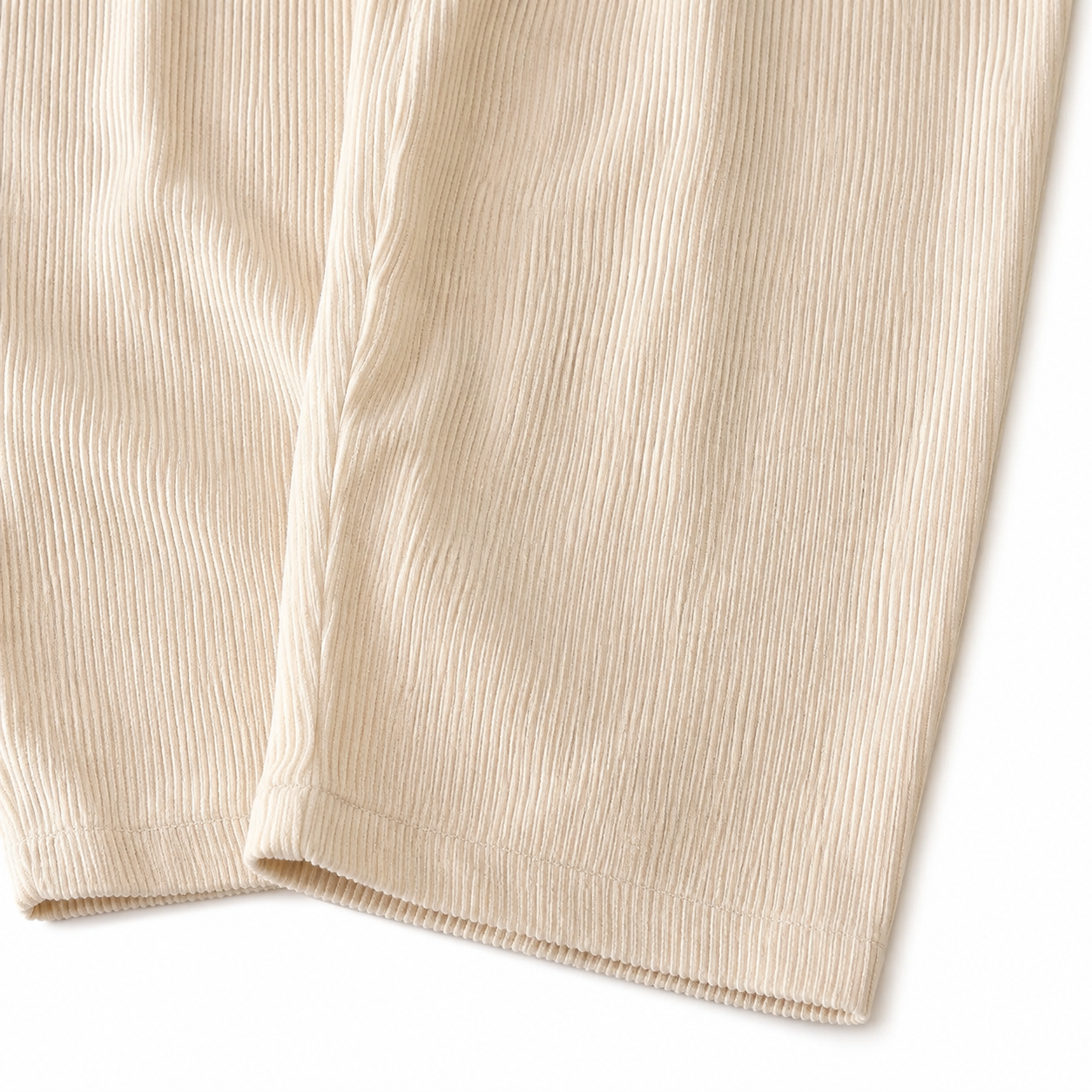 Close-up of the corduroy texture and pant leg hem on the ivory overalls.