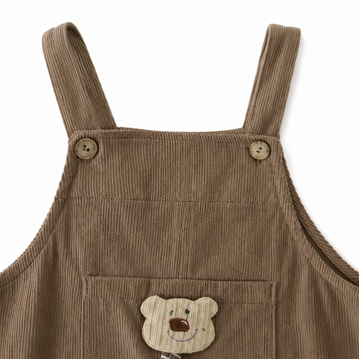 Close-up of the shoulder strap and button detail on the taupe overalls.