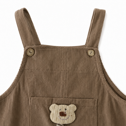 Close-up of the shoulder strap and button detail on the taupe overalls.