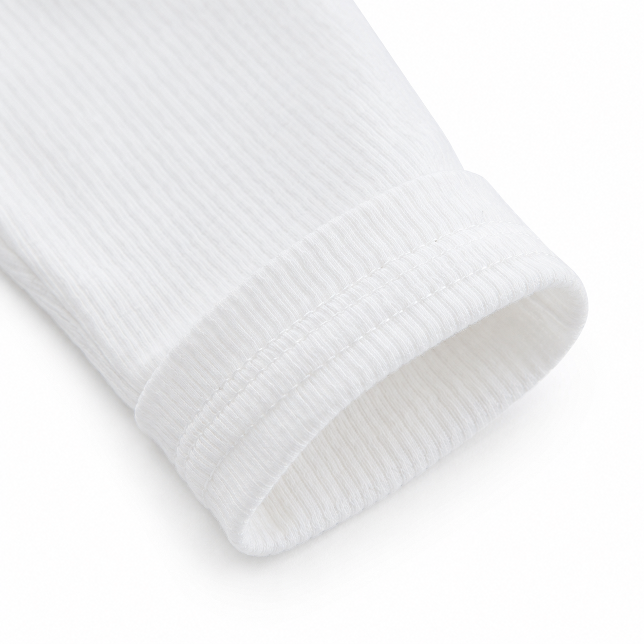Close-up of the sleeve cuff detail on a white girls long sleeve cotton top.