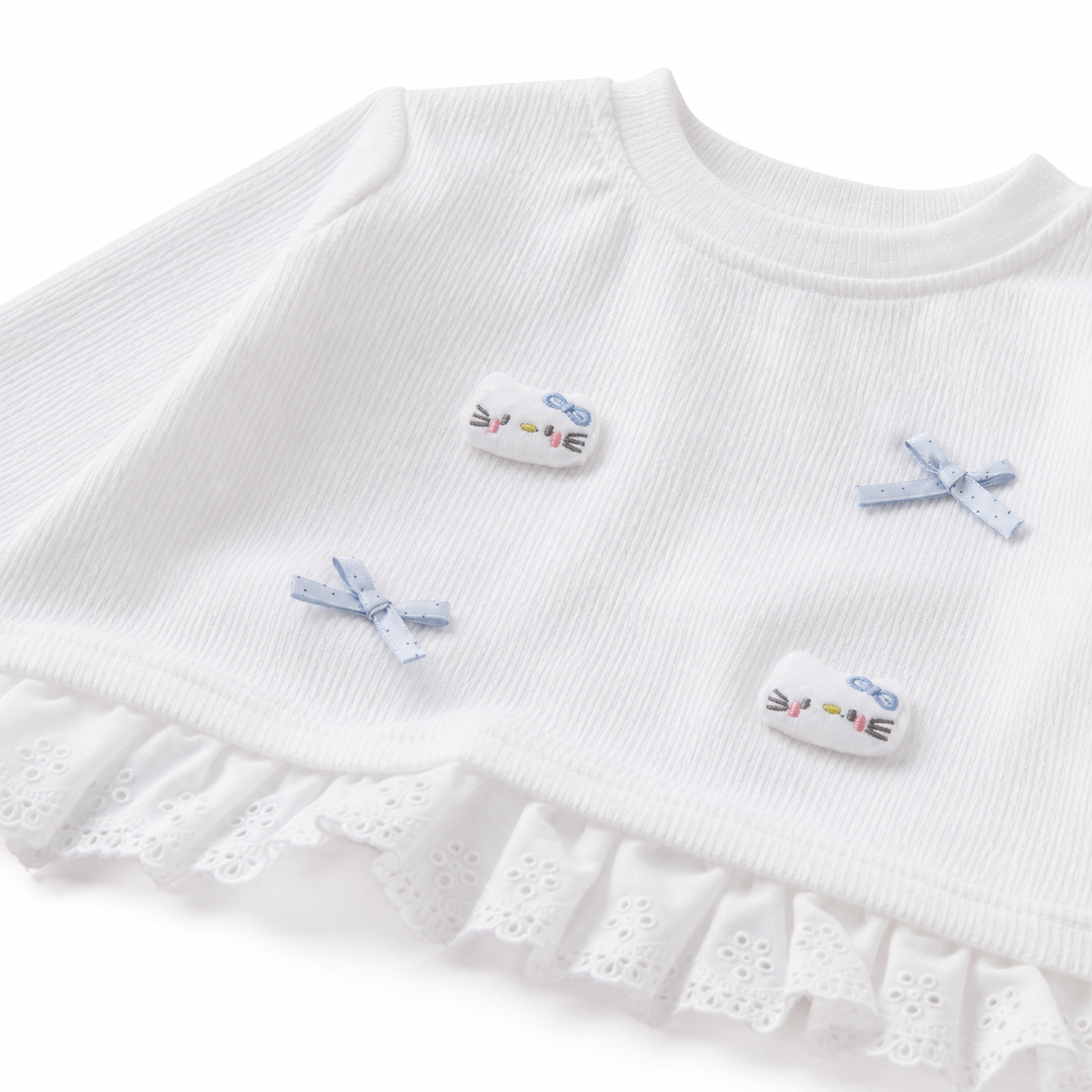 Close-up of the cotton rib texture and ruffle hem on a white girls top.