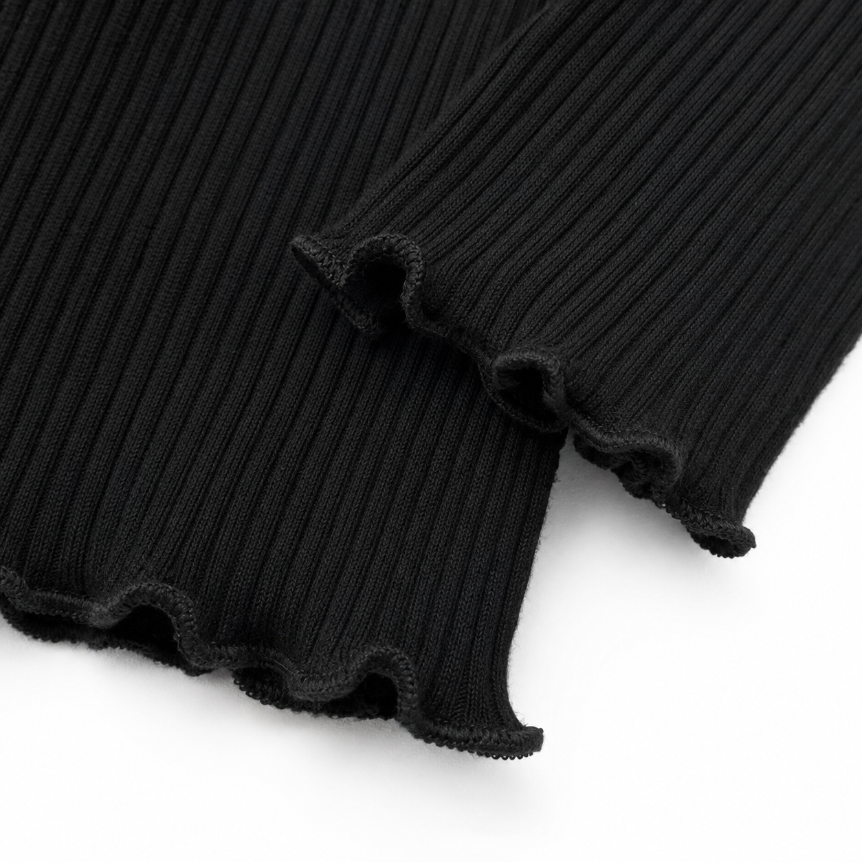 Close-up of the black lettuce-edge hem and ribbed knit detail.