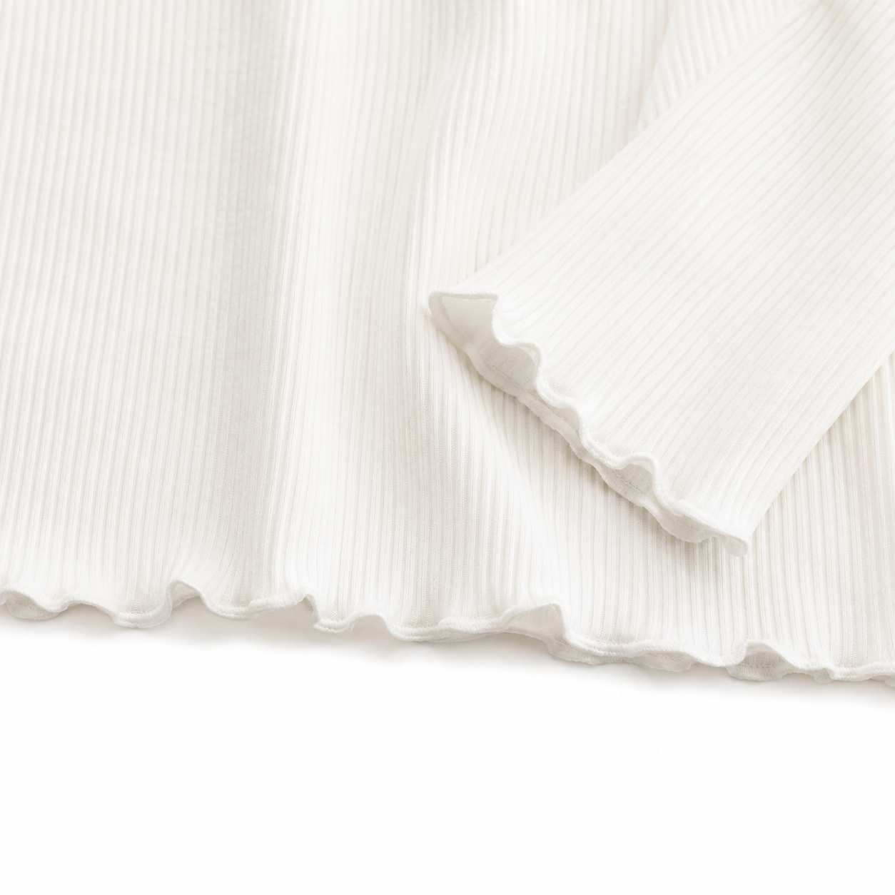 Close-up of the ivory lettuce-edge hem and ribbed knit detail.