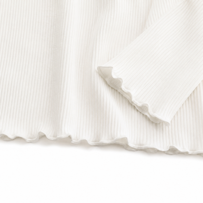 Close-up of the ivory lettuce-edge hem and ribbed knit detail.