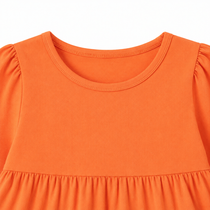 Close-up of the round neckline and gathered shoulder detail on the orange girls dress.