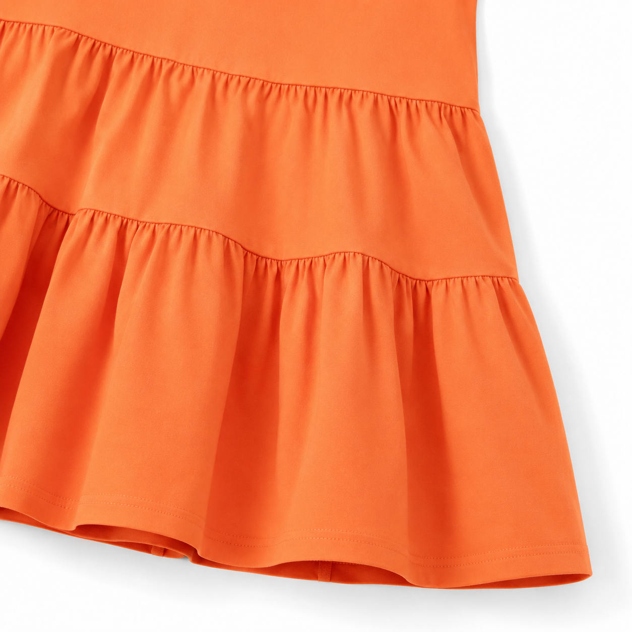 Close-up of the gathered tiered skirt and hem detail on the orange girls dress.