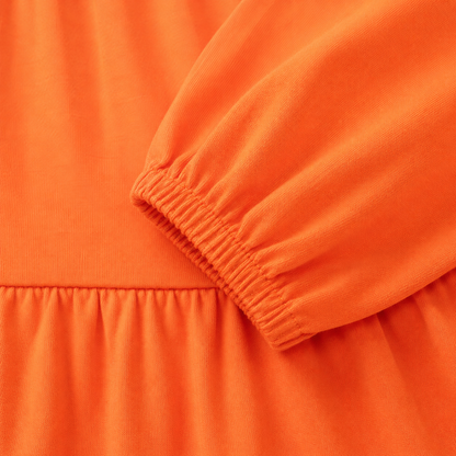 Close-up of the elastic cuff and cotton fabric texture on the orange long sleeve dress.
