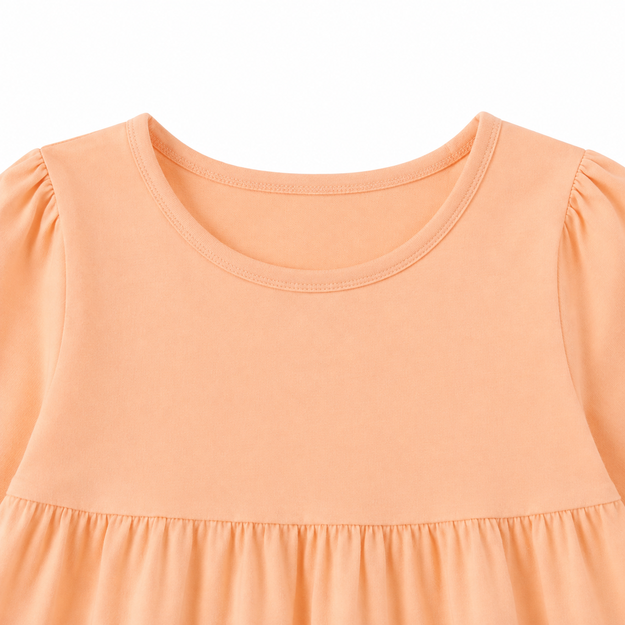 Close-up of the round neckline and gathered shoulder detail on the peach girls dress.