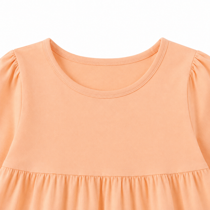 Close-up of the round neckline and gathered shoulder detail on the peach girls dress.